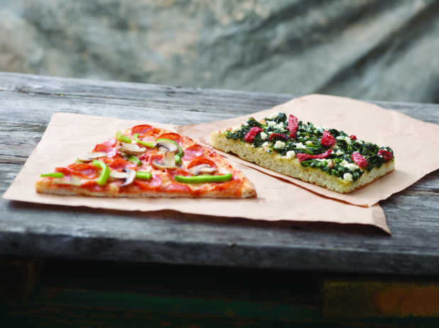 Jumbo Deluxe Pizza Slice and Romano Pizza al Taglio Slice on Kraft Paper on a Weathered Wooden Table – Variation 2
