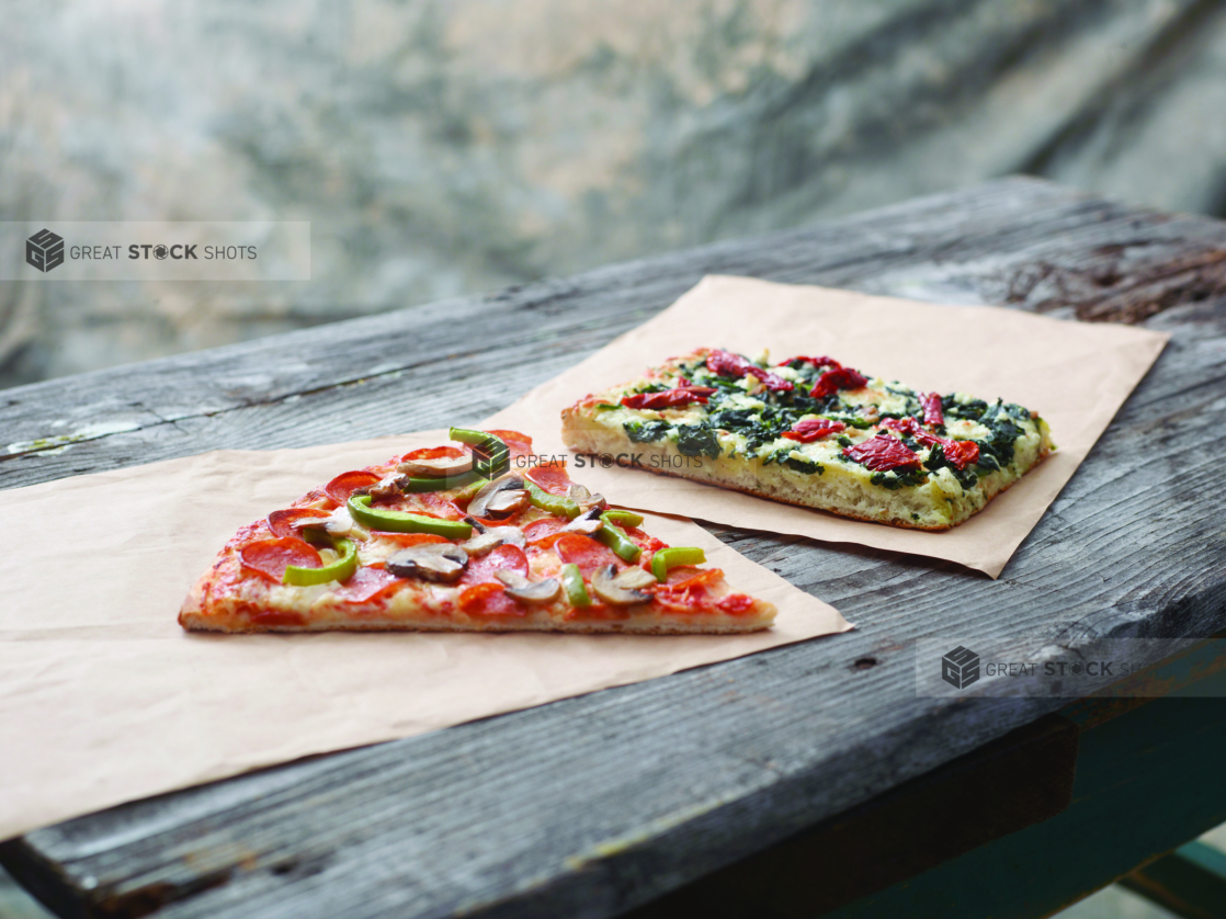 Jumbo Deluxe Pizza Slice and Romano Pizza al Taglio Slice on Kraft Paper on a Weathered Wooden Table