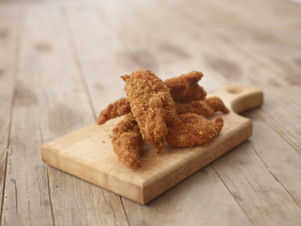 Deep Fried Breaded Chicken Tenders on a Wooden Cutting Board on a Weathered Wooden Surface