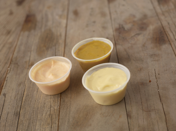 Close Up of a Trio of Dipping Sauces in Plastic Take-Out Container Cups on a Weathered Wooden Surface