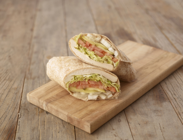 Close Up of a Cut Grilled Chicken Wrap with Fresh Vegetables on a Wooden Cutting Board on a Weathered Wooden Surface