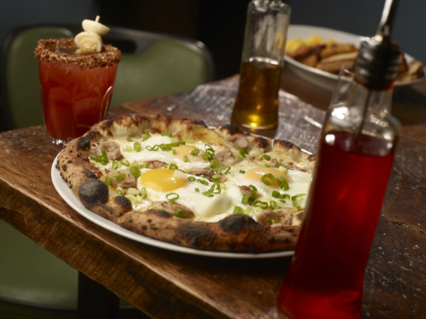 Neopolitan-Style Breakfast Pizza with Sunny Side Up Fried Eggs, Breakfast Sausage and Green Onions and a Caesar Cocktail in a Restaurant Setting