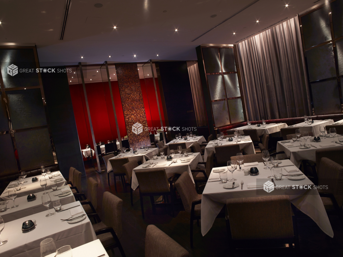 Classy, High-End Restaurant Interior with Multiple Tables for Formal, Intimate Dining and a Large Red Feature Wall