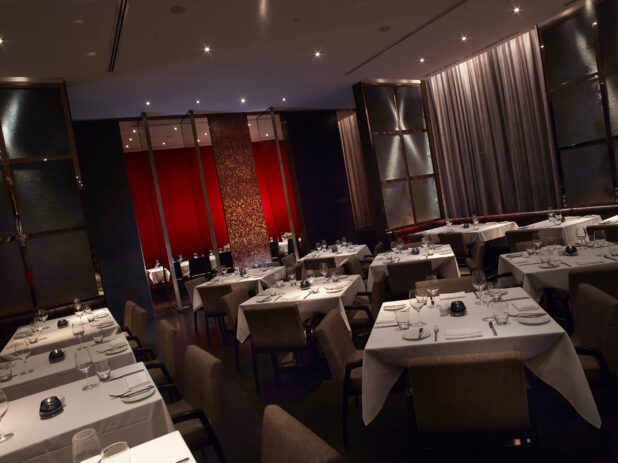Classy, High-End Restaurant Interior with Multiple Tables for Formal, Intimate Dining and a Large Red Feature Wall