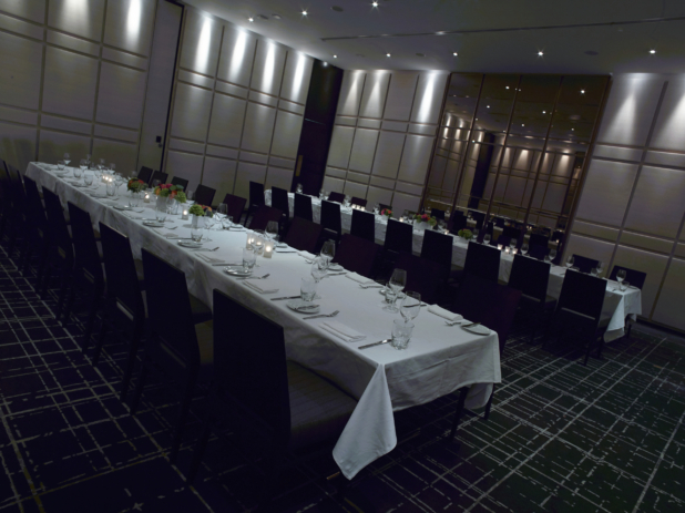 Classy, High-End Restaurant Banquet Hall with Long Rectangular Banquet Seating with Formal Table Settings and Moody Lighting for a Large Formal Reception Setting
