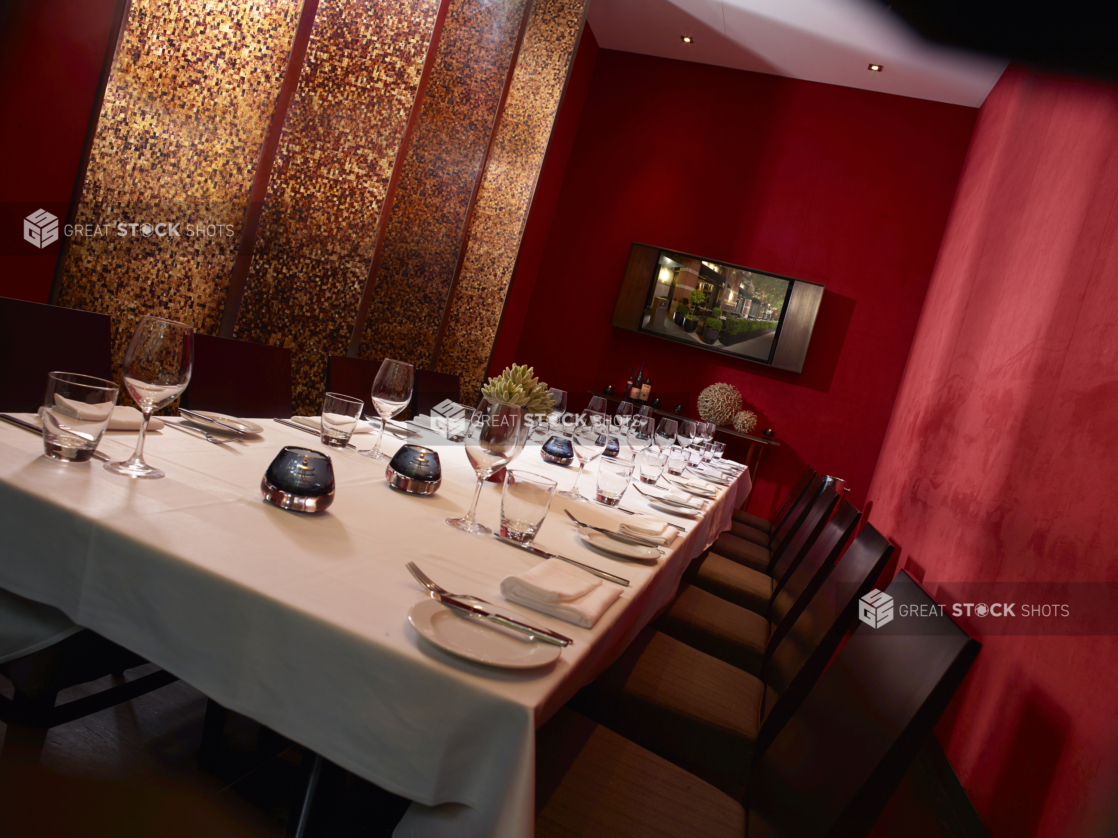 Private Dining Room with Long Banquet Table, Seating and Formal Table Setting with Red Walls and Gold Mosaic Panels and Flat Screen TV