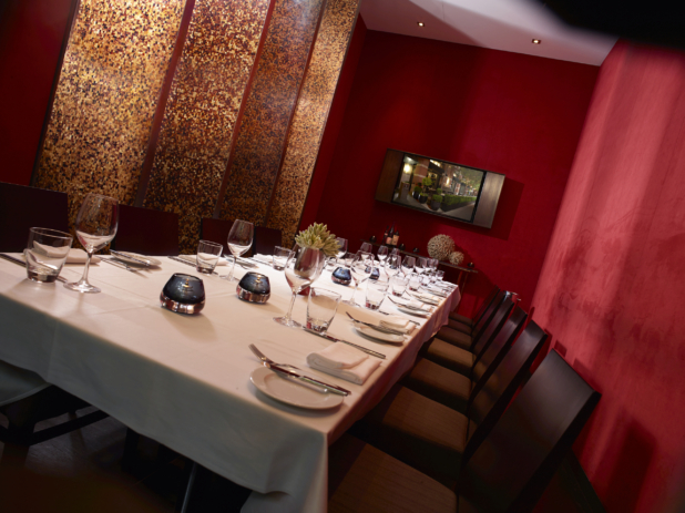 Private Dining Room with Long Banquet Table, Seating and Formal Table Setting with Red Walls and Gold Mosaic Panels and Flat Screen TV