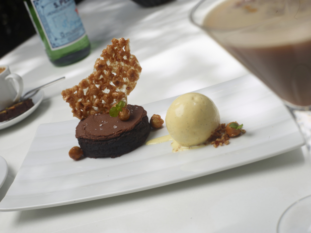 Dessert Platter of Chocolate Gateau with Nut Brittle and French Vanilla Ice Cream on a White Rectangular Dish on a White Table Cloth in an Outdoor Dining Setting