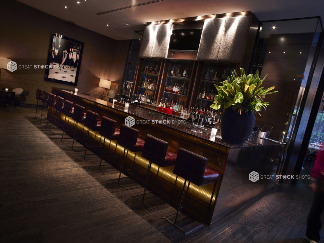 Bar Lounge Area in a Classy, High-End Restaurant Interior with Dark Wood Flooring, Moody Lighting and Red Leather Bar Stools