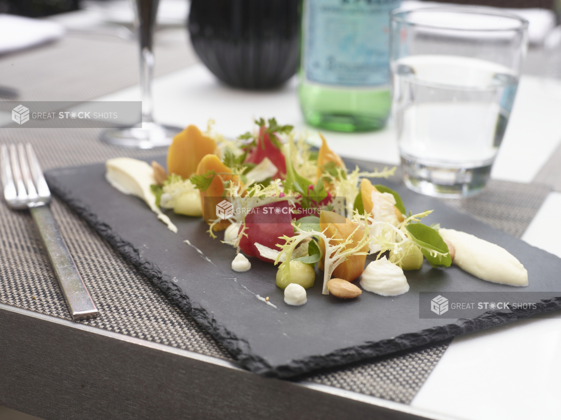 Golden and Red Beet Salad with Frisée, Baby Spinach and Whipped Chèvre on a Black Slate Platter on a Placemat in an Outdoor Dining Setting