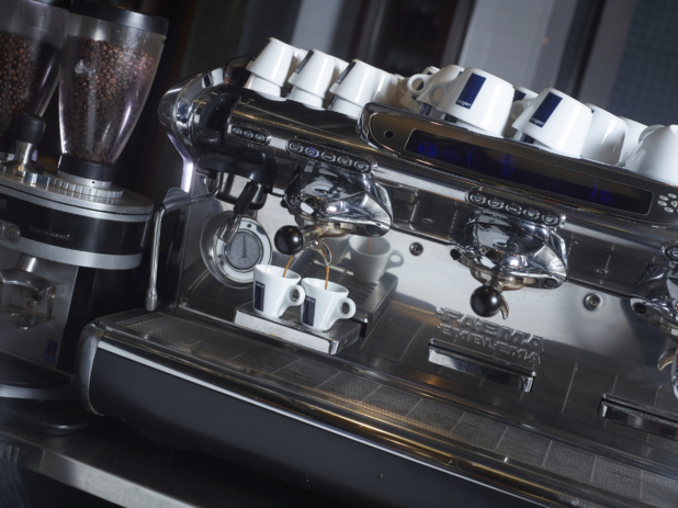 Commercial Espresso Coffee Machine Pouring Espresso into Two Ceramic Cups in a Restaurant Coffee Counter Setting