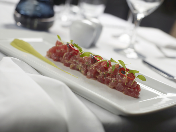 Ahi Tuna Tartare with Microgreens, Yuzu Dressing and Avocado Purée on a White Rectangular Platter on a White Table Cloth Table Setting