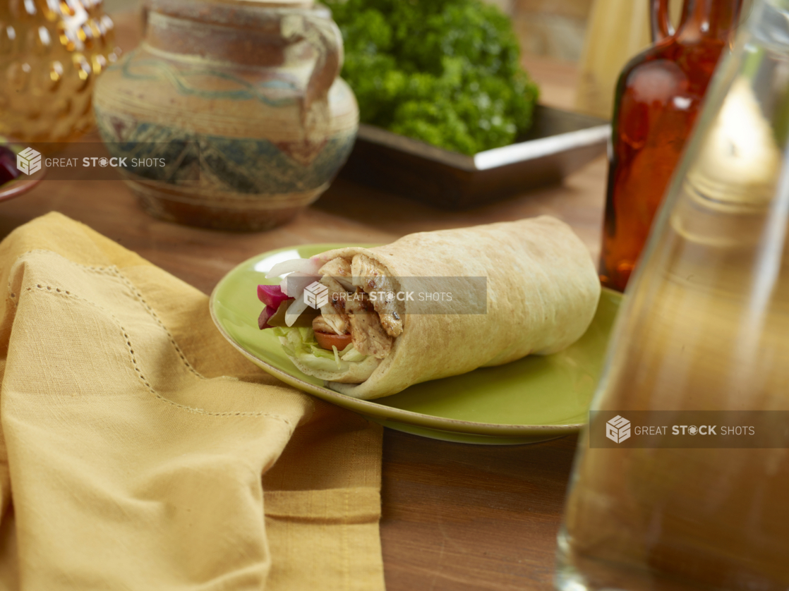 Chicken Souvlaki Pita Wrap with Pickled Veggies and Fresh Vegetables on a Round Ceramic Dish on a Wooden Table in an Indoor Setting