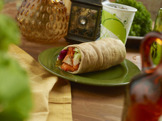 BBQ Chicken Kebab Pita Wrap with Pickled Veggies and Fresh Vegetables on a Round Ceramic Dish with a Fountain Soda on a Wooden Table in an Indoor Setting