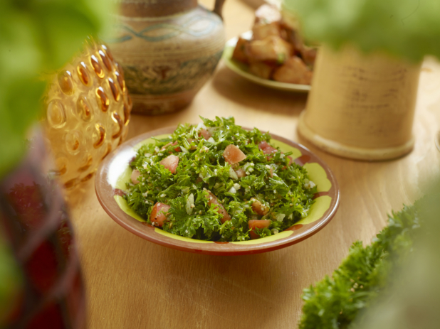 A Colourful Ceramic Dish of Tabbouleh - Parsley, Tomato, Onion and Bulgur Salad - on a Wooden Table in an Indoor Setting