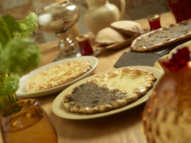 Middle Eastern Style Flatbreads with Cheese and Za'atar Spice Toppings on Round Dishes on a Wooden Table in an Indoor Setting