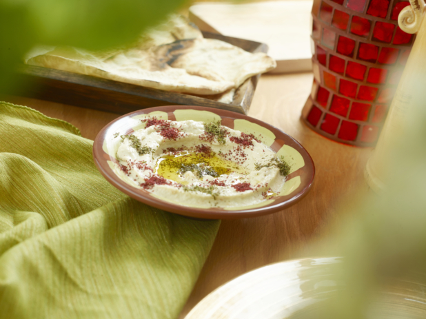 Middle Eastern Baba Ghanoush with Olive Oil and Spices and Pita Bread on a Wooden Table with a Red Mosaic Vase and Green Table Cloth