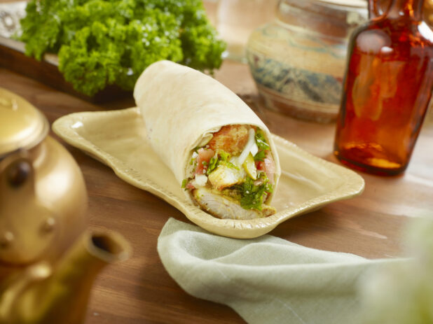 Fried Fish Pita Wrap with Tabbouleh on a Rectangular Ceramic Dish on a Wooden Table in an Indoor Setting