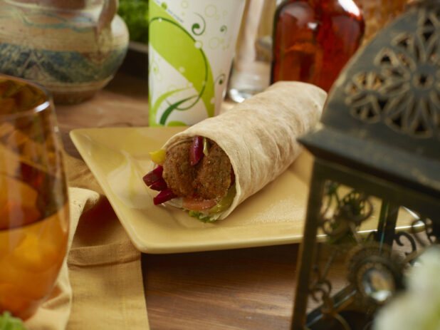 Falafel Pita Wrap with Pickled Veggies and Fresh Vegetables and a Fountain Soda on a Rectangular Ceramic Dish on a Wooden Table in an Indoor Setting
