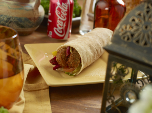 Falafel Pita Wrap with Pickled Veggies and Fresh Vegetables and a Can of Cola on a Rectangular Ceramic Dish on a Wooden Table in an Indoor Setting