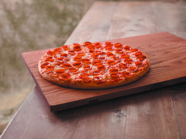 Whole Pepperoni Pizza on a Wooden Cutting Board on a Wooden Table Against a Brown Canvas Background