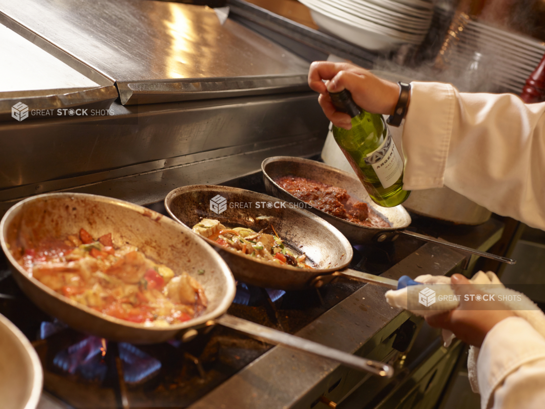 Back of House Kitchen Setting with Chef's Hands Cooking and Preparing to Flambé Over a Gas Fire Stove