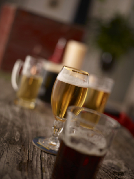 Assorted Glasses of Beer and Lager on an Aged Wooden Surface in an Indoor Restaurant Setting