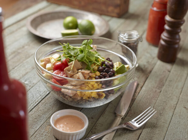 Large Glass Bowl with Cubed Grilled Chicken, Corn, Black Beans, Avocado, Cherry Tomatoes, Cheese and Pea Shoots on a Weathered Wooden Surface in an Indoor Setting - Variation