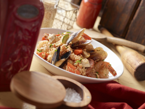 Large White Bowl with a Spanish Seafood Paella on a Wood Surface in an Indoor Setting