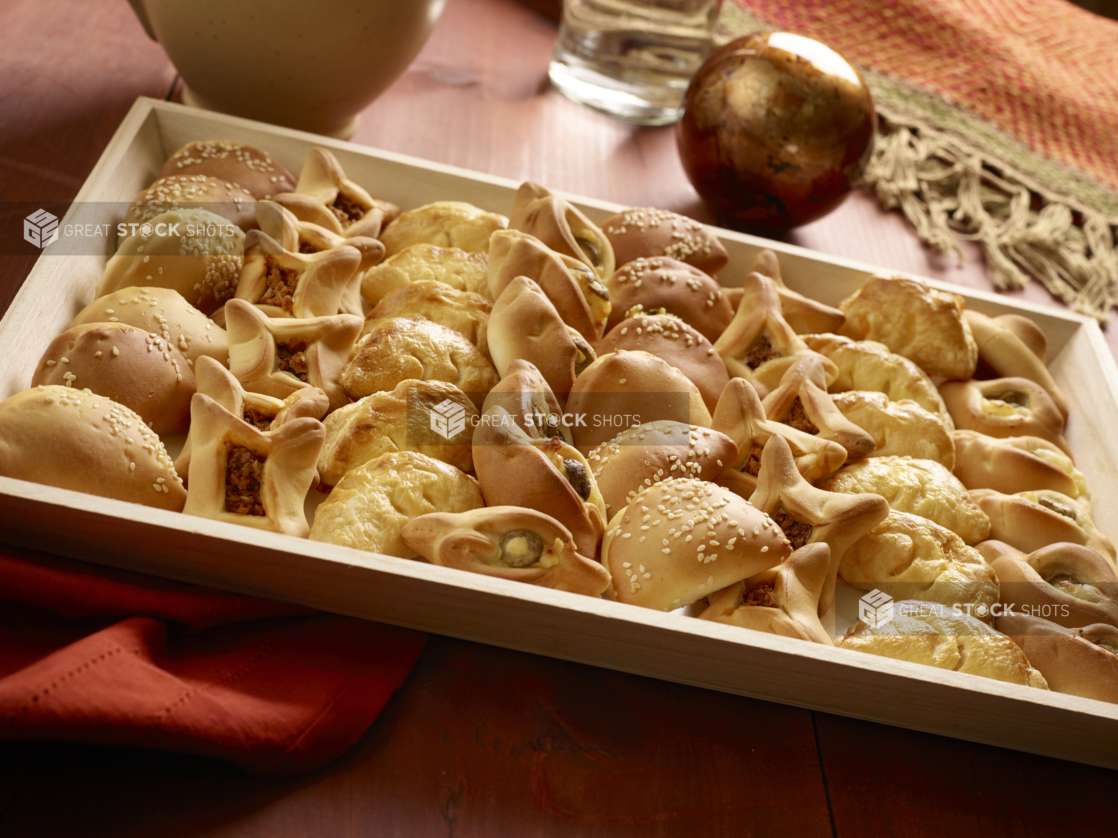 Large Middle Eastern Savoury Pie Platter (zaatar, safeeha, fatayer) in a Rectangular Wooden Serving Tray for Catering on a Wooden Table in an Indoor Setting