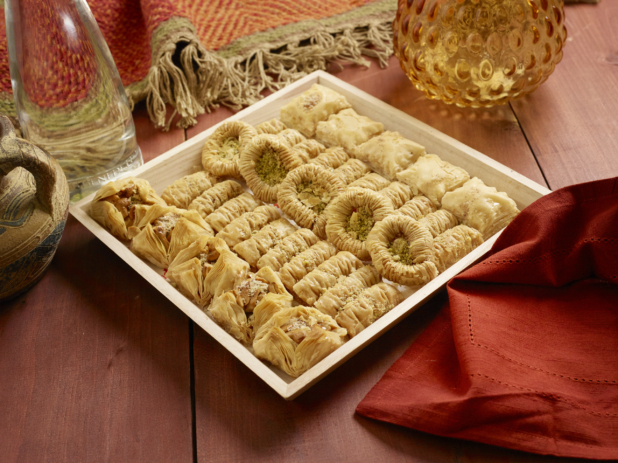 Small Shallow Square Wood Serving Tray of Assorted Baklava for Catering on a Wooden Table with Red Cloth Napkin in an Indoor Setting