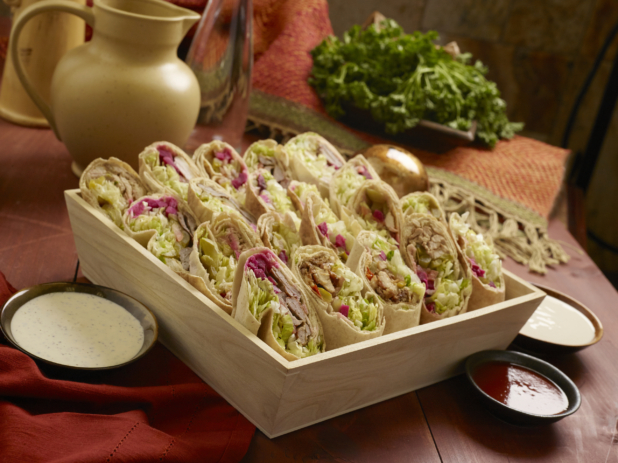 Assorted Middle Eastern Pita Wraps (Chicken and Beef Shawarma, Chicken and Beef Kebabs) in a Deep Square Wood Serving Tray for Catering with Dipping Sauces on a Wooden Table in an Indoor Setting