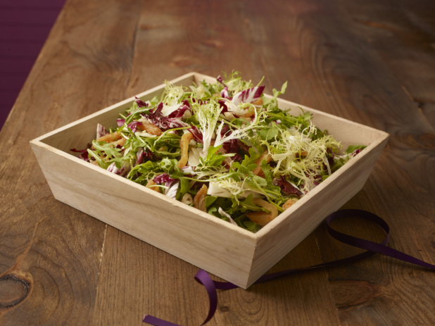 Spring mix salad with roasted yellow peppers in a wood catering box on a wood background, close-up
