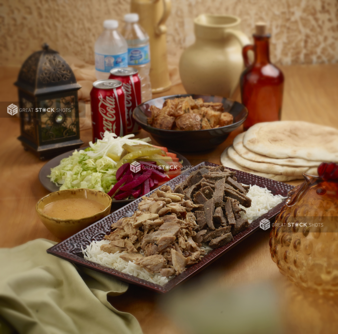 A Family Special Combo of Beef and Chicken Shawarma with Fresh and Pickled Vegetables, White Rice, Roasted Garlic Potatoes, Pita Bread and Cold Drinks