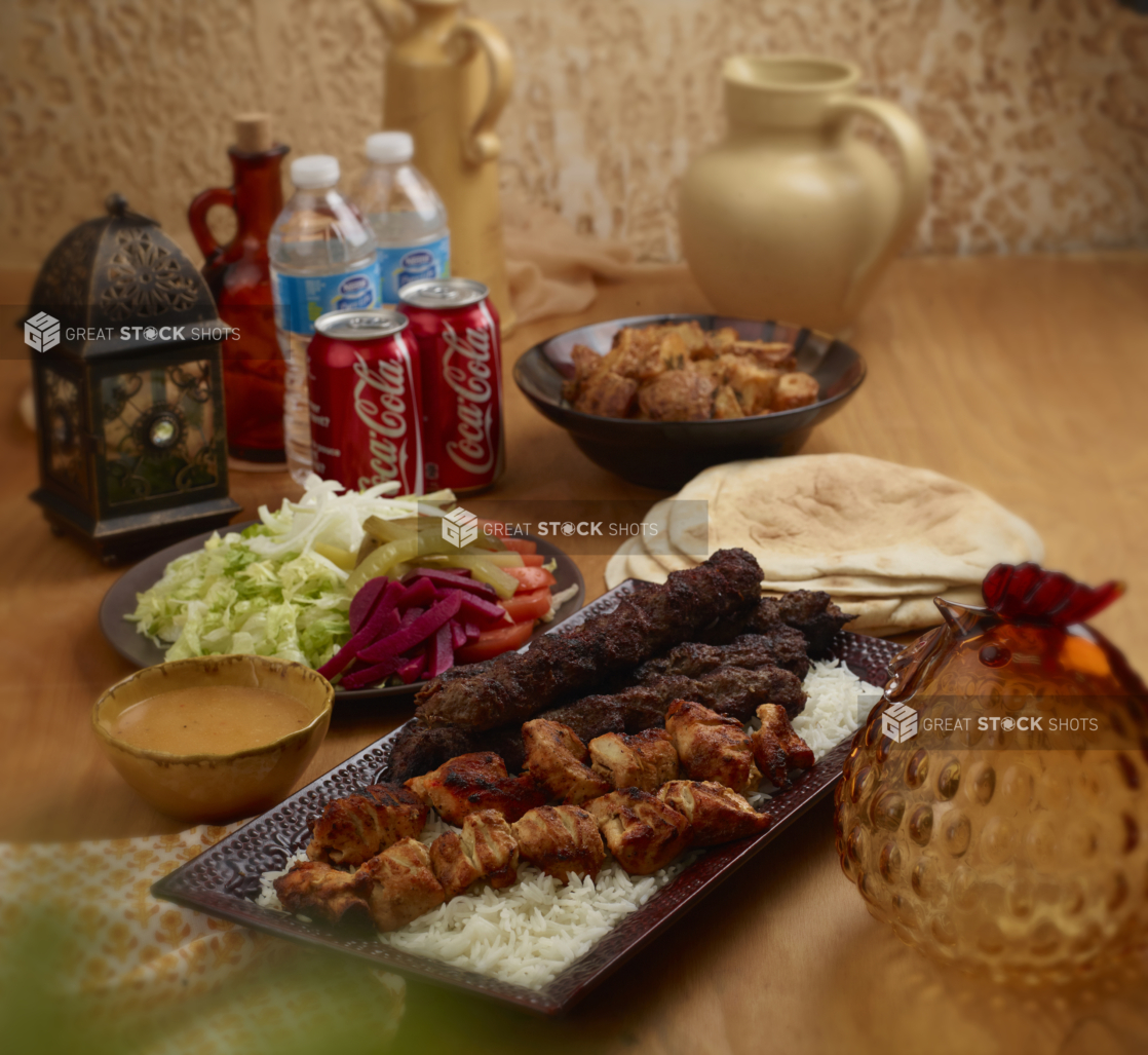 A Family Special Combo of Beef and Chicken Skewers with Fresh and Pickled Vegetables, White Rice, Roasted Garlic Potatoes, Pita Bread and Cold Drinks