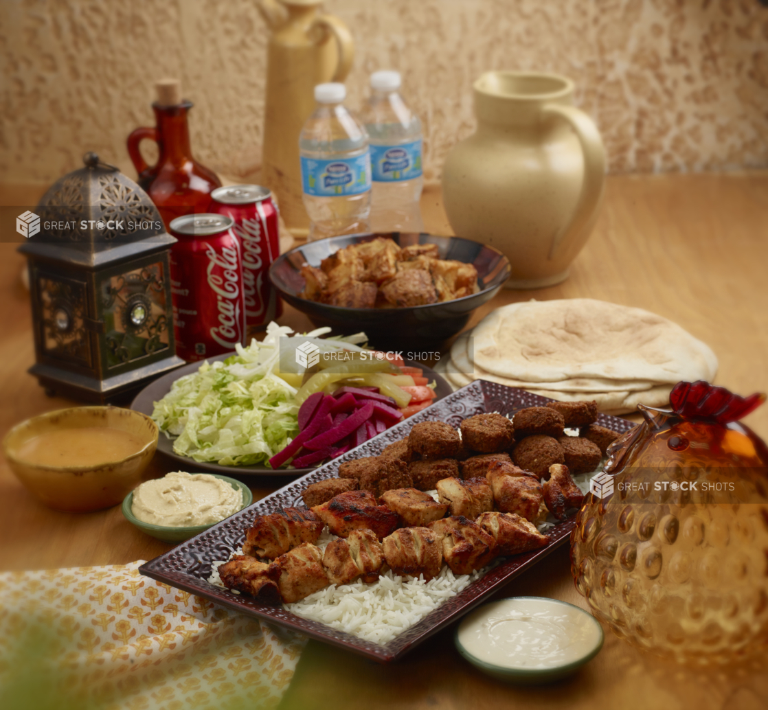 A Family Special Combo of Falafel Balls and Chicken Skewers with Fresh and Pickled Vegetables, White Rice, Roasted Garlic Potatoes, Pita Bread and Cold Drinks