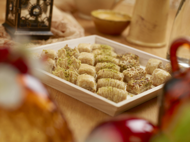 A Close Up of a Wooden Tray of Assorted Mini Baklava Sweets on a Wooden Table in an Indoor Setting - for Catering