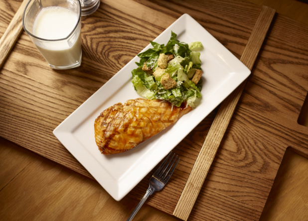 Overhead View of a Kids Grilled Salmon Teriyaki and Caesar Salad Combo Meal on a Rectangular White Ceramic Platter on a Wooden Cutting Board in an Indoor Setting