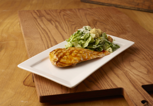 Kids Grilled Salmon Teriyaki and Caesar Salad Combo Meal on a Rectangular White Ceramic Platter on a Wooden Cutting Board in an Indoor Setting