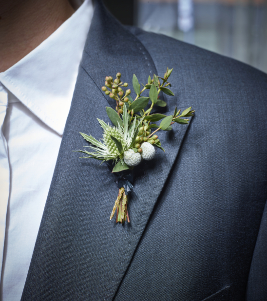 Close Up of a Young Pine Boutonnière Arrangement on the Lapel of a Man Wearing a Blue-Grey Suit