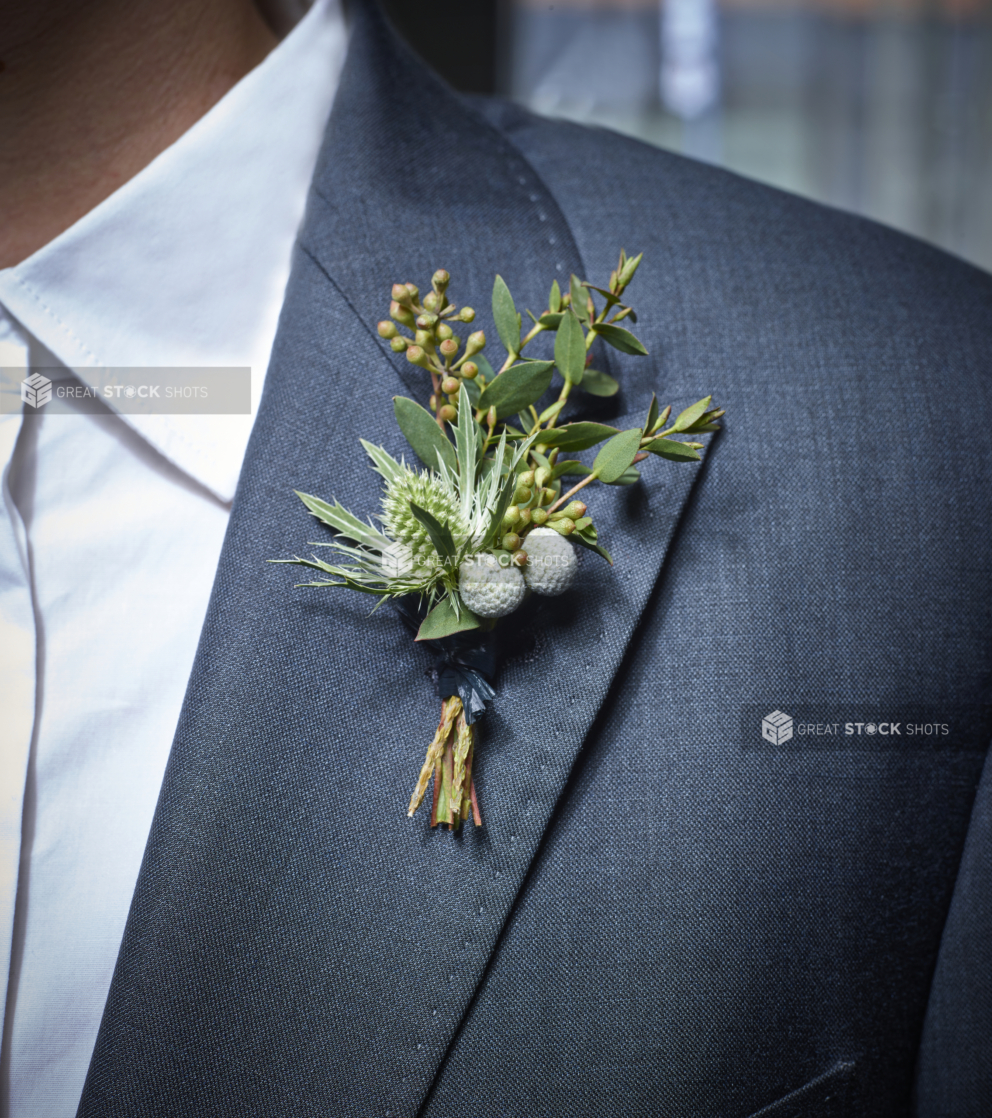 Close Up of a Young Pine Boutonnière Arrangement on the Lapel of a Man Wearing a Blue-Grey Suit