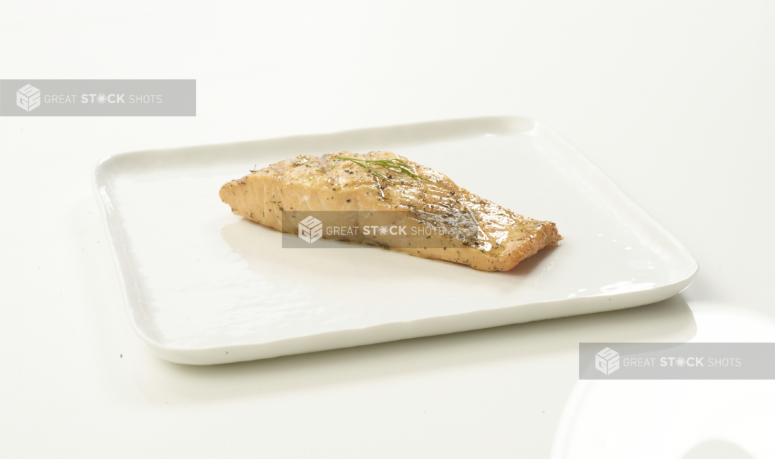 Poached salmon with dill garnish on a white plate