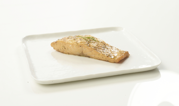 Poached salmon with dill garnish on a white plate