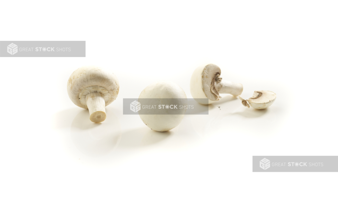 Whole raw white button mushrooms on a white background