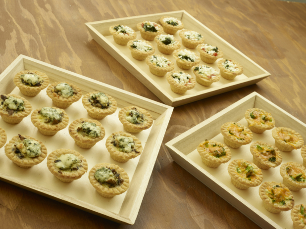 Shallow Wood Serving Trays of Assorted Mini Quiches (Spinach and Mushroom, Cheddar and Broccoli, Quiche Lorraine) for Catering on a Wooden Table