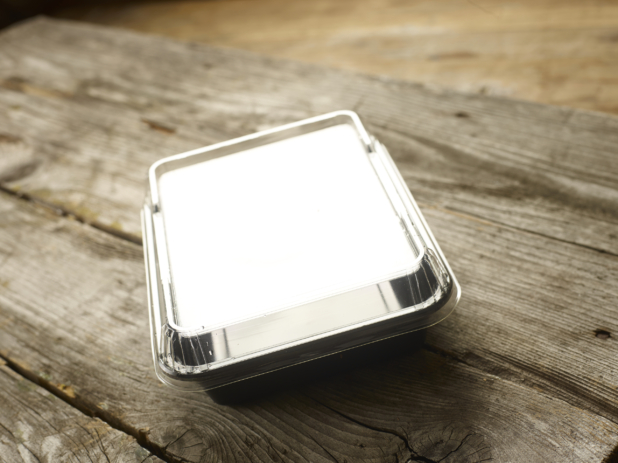 Rectangular Plastic Take-Out Container with Clear Lid and Black Base on Aged Wooden Table - Closed Lid