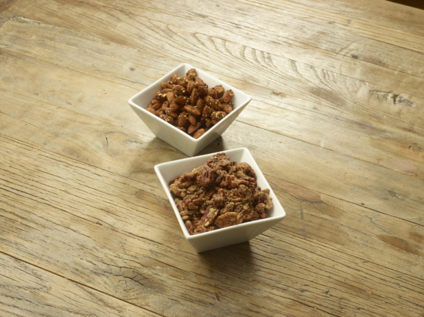Two White Square Bowls Filled with Smoked Pecans and Almonds and Assorted Nuts on a Wooden Table