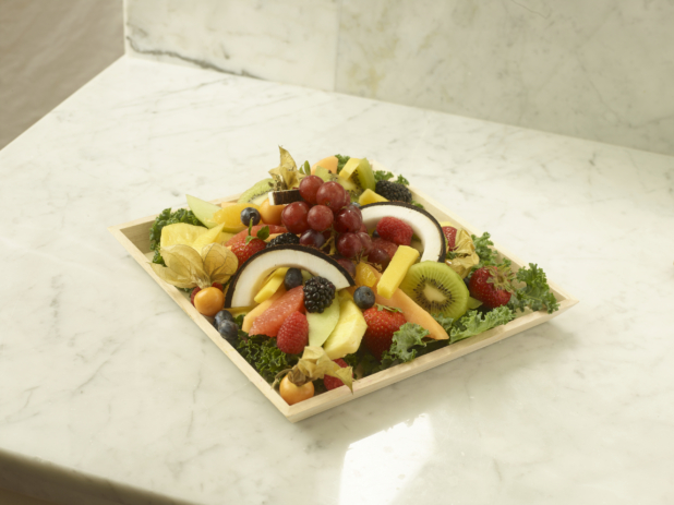 Assorted Sliced and Whole Fruits on a Bed of Romaine Lettuce in a Square Wood Tray on a Marble Surface - for Catering