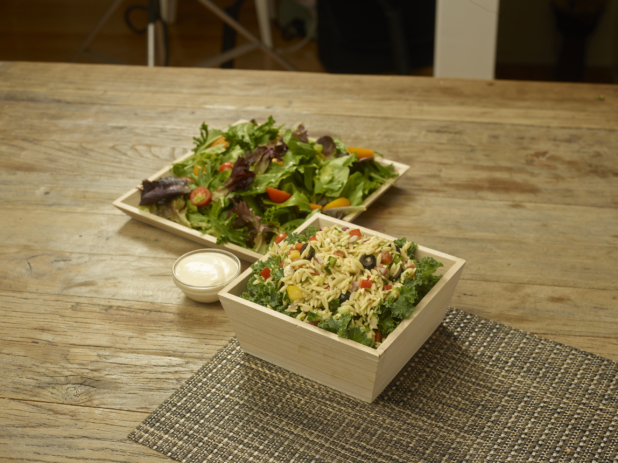 Catering Salad Combo with Spring Mix Salad and Orzo Pasta Salad in Wood Serving Trays with a Creamy Dressing on a Wooden Table