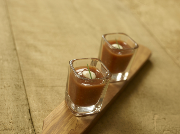 Two Shot Glasses of Cold Gazpacho Soup on a Wooden Paddle on a Wooden Table - for Catering